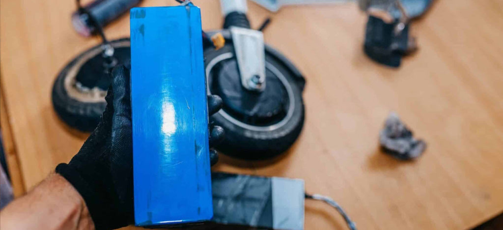 Person holding a blue rectangular object with a wooden surface and parts in the background