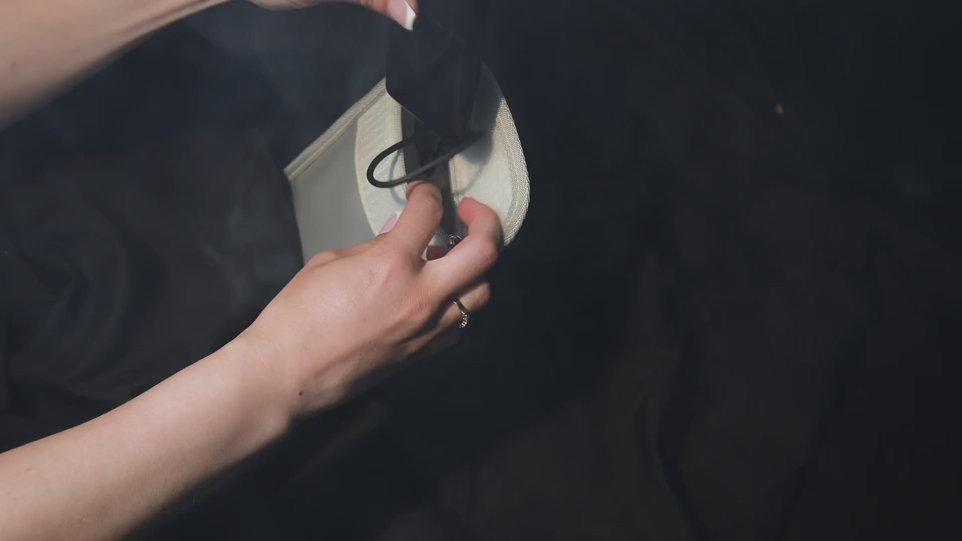 Load video: A person’s hands carefully placing a black portable powerbank into a Fire Blitza pouch, demonstrating the secure internal pocket and oxygen-depleting ziplock technology.